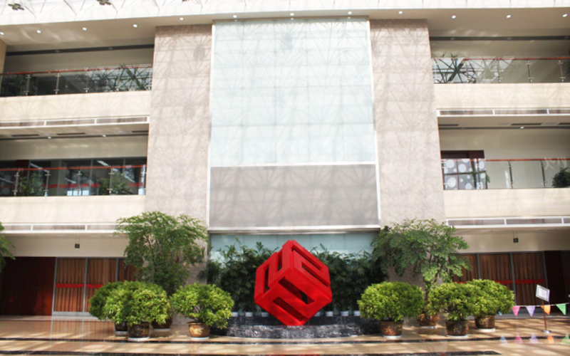 El vestíbulo de la sede de FMWorld está impecable y bien iluminado, con un prominente logotipo cúbico rojo en el centro.